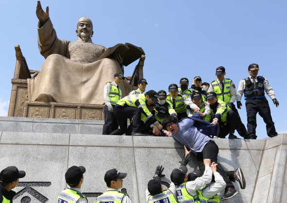 감리교신학대학교 도시빈민선교회 대학생 등이 8일 오후 서울 종로구 세종로 광화문광장 세종대왕상에 올라가 세월호 유가족들의 요구사항 전면 수용 등을 정부에 촉구하며 기습시위를 벌이다 경찰에 연행되고 있다.  이종근 기자 root2@hani.co.kr