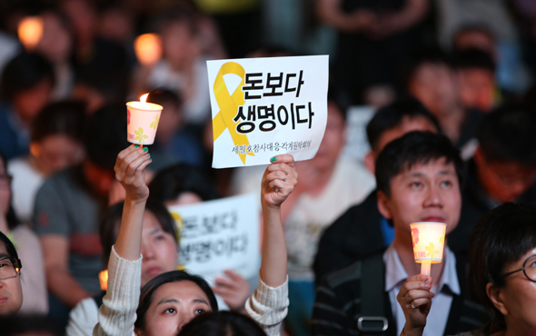 서울 청계광장에서 열린 ‘세월호 참사 추모 5·17 범국민 촛불행동’ 집회에 참여한 한 시민이 ‘돈보다 생명이다’라고 쓰인 손팻말과 촛불을 들어올리고 있다. 　강창광 기자 chang@hani.co.kr