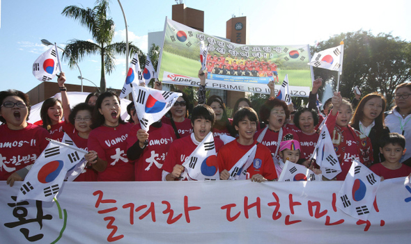 <b>응원 나온 교민들</b> 한국 대표팀이 베이스캠프인 포스두이구아수에 입성한 11일 오전(현지시각) 태극기를 손에 든 교민들이 선수단 숙소 앞에 마중 나와 대표팀을 맞이하고 있다. 포스두이구아수/이정아 기자