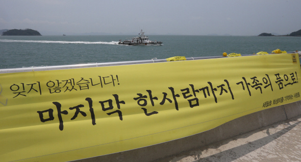 12일 오후 전남 진도 팽목항에 세월호 참사 실종자들이 돌아오기를 기원하는 내용이 적힌 노란 펼침막 뒤로 해경선이 지나고 있다. 지난 8일 밤 희생자 1명이 수습된 뒤로 나흘째 실종자 추가 발견은 없었다. 현재까지 세월호 사고 희생자는 292명, 실종자는 여전히 12명이다. 팽목항의 기다림은 계속된다.  진도/박종식 기자 anaki@hani.co.kr