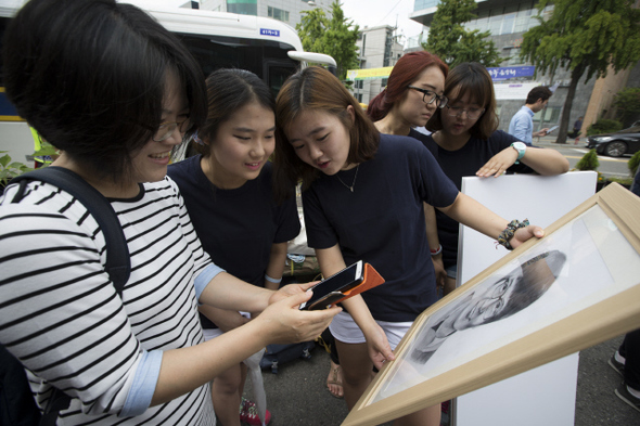 태안 해병대캠프 희생자 이준형군의 어머니 문광숙(왼쪽)씨와 이군의 친구들이 17일 오전 서울 종로구 청운효자동주민센터 앞에서 열린 ‘2013년 태안 사설해병대캠프 참사 1주기, 추모와 전면 재수사 촉구 기자회견’을 마친 뒤 이군의 캐리커처가 담긴 액자와 휴대전화에 저장되어 있는 사진을 번갈아 보고 있다. 어머니 문씨는 캐리커처 속 아들의 사진을 보던 중 “바이올린뿐만 아니라 피아노도 잘 치는 아들이었다. 공부도 잘했다”고 회상했다. 김성광 기자 flysg2@hani.co.kr