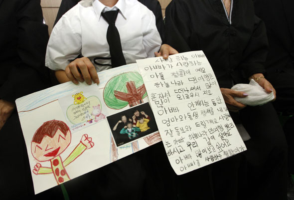 지난 17일 광주 헬기 추락사고로 순직한 강원도소방본부 소속 소방관 5명의 합동분향소가 마련된 강원 춘천시 강원효장례문화원에서, 안병국 소방위의 아들(8)이 직접 그린 그림과 손편지를 들고 있다. 춘천/연합뉴스