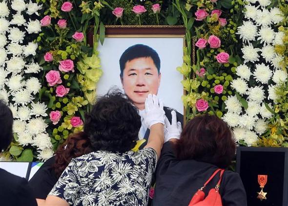 <b>유가족 오열…그 옆에서 김태호 의원은 기념사진</b> 헬기 추락사고로 순직한 강원도소방본부 소속 소방관 5명의 합동 영결식이 열린 22일 오전 강원도청 별관 광장에서 유가족들이 영정사진을 만지며 오열하고 있다. 춘천/연합뉴스