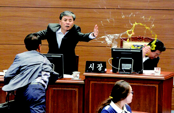 프로야구 구단 엔씨(NC) 다이노스 새 야구장을 두고 경남 창원시 진해야구장 백지화에 반대하는 진해지역 출신 김성일 창원시의원이 16일 오후 창원시의회 본회의장에서 안상수 창원시장에게 달걀 2개를 던지고 있다. 최근 창원시가 진해구 옛 육군대학 터로 결정된 엔씨 다이노스 야구장 입지를 마산종합운동장으로 변경하면서 야구장 이전 문제를 두고 진해구민들의 반발이 확산되고 있다.  경남신문 제공