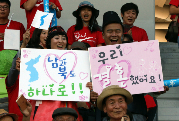 2014 인천아시안게임 기간 남과 북을 함께 응원하는 ‘아리랑 통일 응원단’으로 경기장을 찾은 신혼부부 유종철(오른쪽), 김형남씨가 20일 오후 인천 남동구 수산동 남동아시아드럭비경기장에서 홍콩과 예선전을 치르는 북한 여자축구 선수를 응원하고 있다. 이들은 이날 서울에서 결혼식을 치렀지만 신혼여행도 미룬 채 인천을 찾았다.   인천/이정용 선임기자 lee312@hani.co.kr