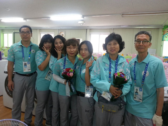 북한 여자축구 선수들로부터 꽃다발을 받은 자원봉사자들이 즐거운 표정을 짓고 있다.