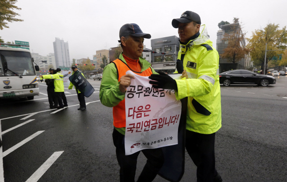 정부의 공무원연금 개편안에 반대하는 전국공무원노동조합(공무원노조) 조합원들이 20일 오후 서울 종로구 세종로 정부서울청사 후문 앞에서 결의대회를 한 뒤, 한 조합원이 1인 시위를 하려 청와대 쪽으로 향하자 경찰이 막아서고 있다. 공무원노조 이충재 위원장과 임원, 14개 지역본부장 등 19명이 이날 정부의 공무원연금 개편안에 반발해 집단 삭발했다. 이종근 기자 root2@hani.co.kr 