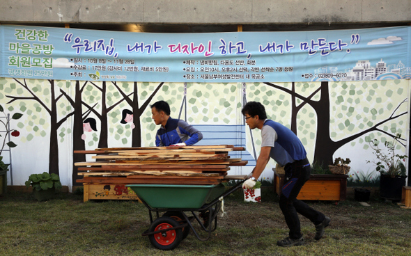 건강한 농부 협동조합이 만든 목공소 앞에서 동네에서 얻어온 폐자재 팔레트를 옮기는 사람들.