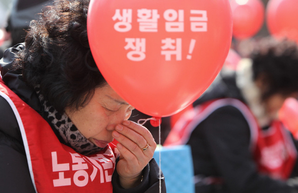 실질적인 최저생계비를 보장하기 위해 생활임금제를 도입하는 지자체가 잇따르고 있다. 2011년 대학 청소노동자 파업 대회에서 한 참가자가 ‘생활임금 쟁취’가 적힌 풍선을 들고 있다. 이종근 기자 root2@hani.co.kr