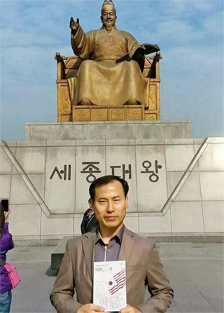 최돈우 경위가 지난달 28일 서울 광화문광장 세종대왕 동상 앞에서 영어 오·남용을 비판한 자신의 책 <영어에 미친 나라, 대한미(美)국>을 선보이고 있다. 사진 최돈우 경위 제공