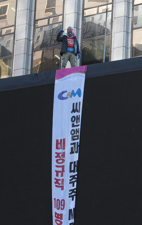 케이블방송사 씨앤앰 비정규직 노동자 두 명이 12일 오전 서울 중구 태평로에 있는 20미터 높이 옥외광고판 위에서 비정규직 해고 문제 해결을 요구하며 고공 농성을 벌이고 있다. 이들이 속한 희망연대노조는 조합원들이 장기 농성에 필요한 물품들을 준비해 올라갔다며 사쪽이 문제를 해결할 때까지 고공 농성을 이어가겠다고 밝혔다. 신소영 기자 viator@hani.co.kr