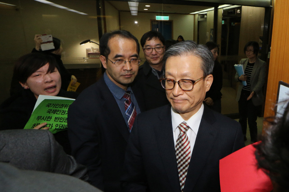 국가인권위원회 설립 13주년을 하루 앞둔 24일 오후 서울 중구 을지로 인권위에서 동성애 차별 발언으로 물의를 빚은 최이우 비상임 인권위원(맨 앞)이 자신의 사퇴를 촉구하며 손팻말 시위를 벌이는 인권단체 활동가들 앞을 지나 전원회의장으로 가고 있다.  이정아 기자