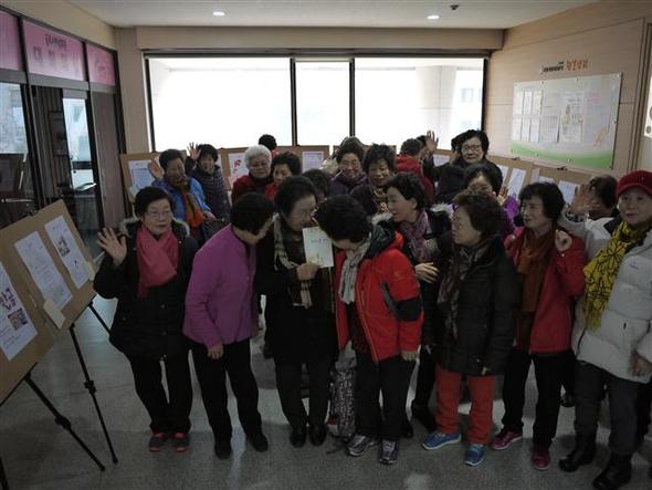 지난달 20일 경기도 군포시 여성회관 2층에서 시화전을 열고 있는 한글교실 할머니들이 진효임 시인이 들고 있는 시집 <치자꽃 향기>를 부러운 듯 바라보고 있다