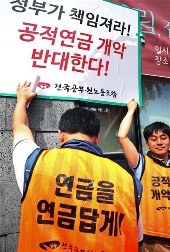 전국공무원노동조합이 18일 서울 청운동 청와대 인근에서 ‘당사자 배제한 공무원연금 개악 밀실 논의 규탄 기자회견’을 하는 도중 일부 조합원이 “정부가 책임져라! 공적연금 개악 반대한다!”고 적힌 피켓을 더 높이 들어올리려 하고 있다. 연합뉴스