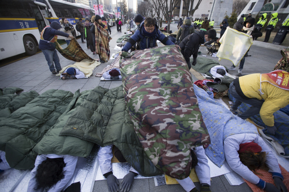 해고자 복직과 정리해고 철폐를 요구하며 오체투지로 청와대를 향해 이동하던 쌍용자동차 해고노동자들과 비정규직 노동자들이 12일 오전 서울 종로구 세종로 정부서울청사 앞 길바닥에서 경찰에 가로막혀 엎드려 있자 함께 있던 동료가 담요를 덮어주고 있다.  김성광 기자 flysg2@hani.co.kr