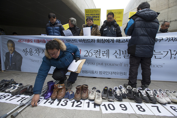 쌍용자동차 범국민대책위원회가 13일 오전 쌍용차 티볼리 신차 발표회가 열린 서울 동대문구 동대문디자인플라자 앞에서 쌍용차 해고 노동자 26명의 죽음을 추모하는 의미의 신발 26켤레를 놓고 마힌드라 아난드 회장과의 면담 및 해고자 전원복직을 촉구하고 있다. 김성광 기자 flysg2@hani.co.kr