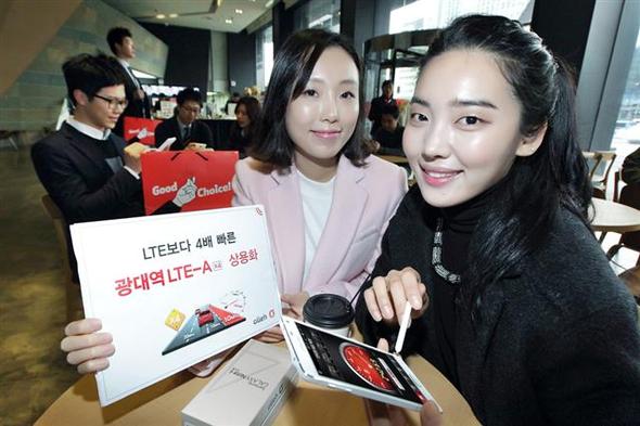 케이티(KT) 직원들이 20일 오전 서울 세종로 올레스퀘어에서 3밴드 LTE-A 상용서비스의 본격 개시와 함께 공식 출시하는 갤럭시노트4 S-LTE 단말기를 홍보하고 있다. 이 단말기의 출고가는 95만7000원이다. 3밴드 LTE-A는 3개 대역 주파수 묶음기술을 적용해 최고 300Mbps(초당메가비트)의 속도를 구현한 통신 서비스로, 이는 기존 LTE의 4배, 3세대(3G)보다는 21배 빠른 것이다.  케이티 제공