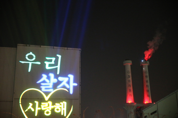 쌍용자동차 고공농성 92일째인 14일 오후 경기도 평택 쌍용자동차 공장앞에서 전국 각지역에서 모인 시민들과 노동자들이 3.14 쌍용차 희망행동 행사를 하고 있다.  행사측에서 쌍용자동차 공장 외벽에 레이저로 글귀를 쏘고 있다.  평택/ 김봉규 기자 bong9@hani.co.kr