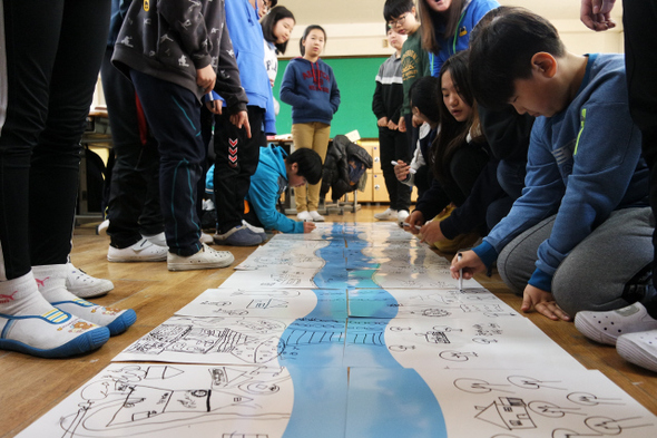 지난 6일 서울 도봉구 월천초등학교에서 열린 ‘프로젝트 웨트’ 물 교육 프로그램의 ‘내가 이 땅의 주인이라면?’ 활동에 참가한 6학년 5반 아이들이 모둠별로 활동지에 그린 강과 주변의 모습을 이어붙여 상-중-하류로 이루어진 큰 강 하나를 완성했다.