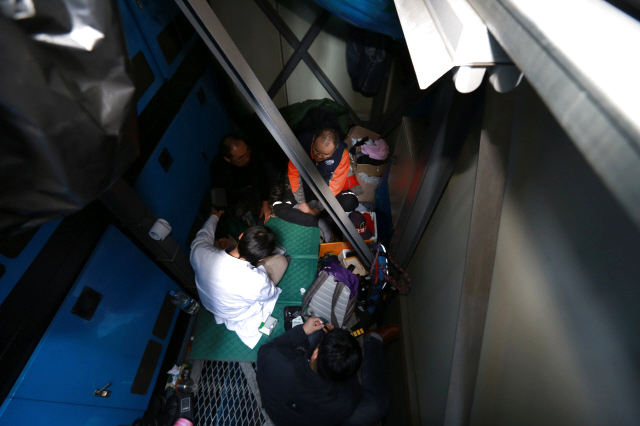 지난 3월24일 이상윤 노동건강연대 대표(녹색병원 직업환경의학과장)가 서울중앙우체국(서울 중구 소공로) 앞 광고탑에 올라 고공농성 중인 강세웅(LG유플러스 비정규직노동자)씨와 장연의(SK브로드밴드 비정규직노동자)씨의 건강을 살피고 있다.