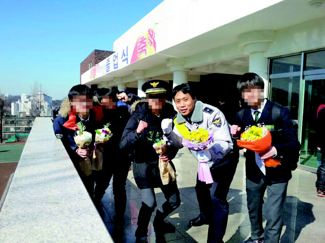지난 2월 서울 관악경찰서 학교전담경찰관 이백형 경위가 서울 관악구 남강고교 졸업식에서 관할지역 학생들과 어울려 사진을 찍고 있다. 사진 관악경찰서 제공