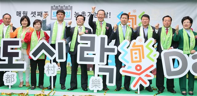 농림축산식품부와 전국경제인연합회, 농협중앙회, 농민단체 등이 11일 국회 후생관 앞에서 ‘다함께 농촌 가는 날’ 캠페인 선포식을 열어 참석자들이 기념사진을 찍고 있다. 도시와 농촌이 함께·상생하면 즐겁다는 뜻으로 ‘도(都)·시(村)·락(樂) DAY’라는 표어를 내세운 이 캠페인은 농촌 일손부족 해소와 도농 상생으로 농업·농촌지역에 활력을 넣고자 기획됐다. 매월 셋째 주 토요일을 ‘전 국민 농촌 가는 날’로 지정해 농촌일손돕기와 농촌체험, 재능기부, 도농교류 등 도농 상생 생활화 및 농촌방문 정례화 문화 조성을 목표로 전개된다.  
연합뉴스 