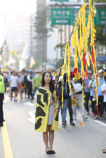 세월호 집회에서 노란 천을 찢어 만든 깃발을 들고 다니는 퍼포먼스를 하고 있는 홍승희씨.