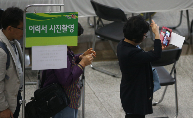 19일 오후 경기도 성남시 중원구 여수동 성남시청에서 열린 ‘구인·구직자 만남의 날’ 행사에 참가한 한 여성이 이력서에 붙일 사진을 찍어주는 부스 앞에서 휴대전화로 자신의 얼굴을 살피고 있다.  성남/신소영 기자 viator@hani.co.kr