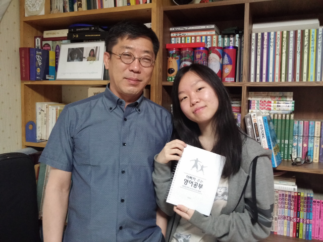 문법을 어려워하는 딸을 위해 영어책 <아빠가 주는 영어공부>를 직접 쓴 하권석씨가 광주의 자택에서 딸 영건양과 함께 웃고 있다. 영건양이 들고 있는 것이 가제본한 하씨의 책이다. 하씨는 현재 이 책을 정식으로 출판하기 위한 절차를 밟는 중이다.  하권석씨 제공