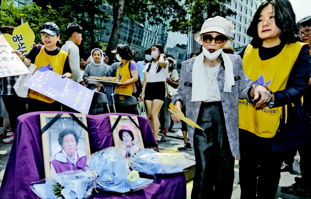 김복동 위안부 피해 할머니(오른쪽 둘째)가 17일 낮 서울 종로구 중학동 주한일본대사관 앞에서 열린 ‘일본군 위안부 문제 해결을 위한 1183차 정기 수요시위’를 마친 뒤 윤미향 정신대문제대책협의회 대표의 손을 잡은 채 자리를 뜨고 있다. 왼쪽으로 지난 11일 돌아가신 김외한(왼쪽), 김달선 할머니의 영정 사진과 추모하는 꽃이 놓여 있다. 이종근 기자 root2@hani.co.kr