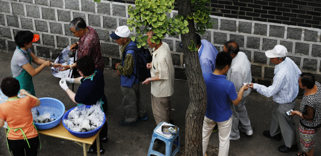 중동호흡기증후군(메르스)의 여파로 자원봉사자들의 발길이 뜸해지고, 인근 무료급식소가 문을 닫은 19일 오전 서울 종로구 원각사 노인무료급식소에서 관계자들이 노인들에게 점심으로 주먹밥을 나눠주고 있다.   이종근 기자 root2@hani.co.kr