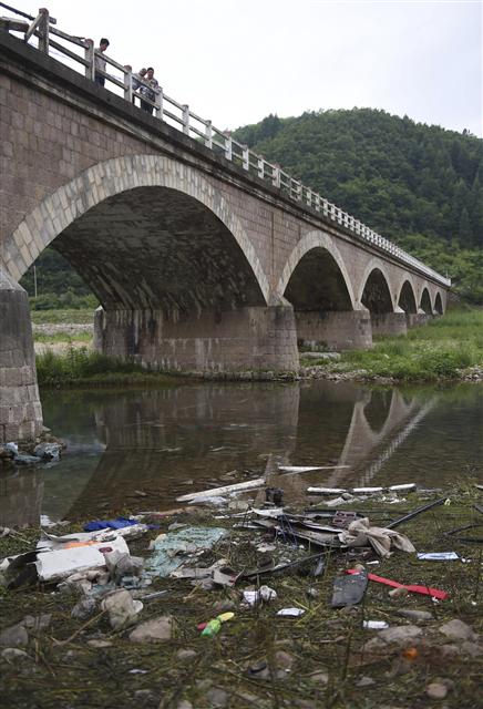 <b>사고 현장</b> 2일 중국 지린성 지안시의 다리 아래에 전날 추락한 버스의 잔해가 널려 있다. 1일 중국 연수를 떠난 행정자치부 소속 지방행정연수원 교육생을 태운 버스가 다리에서 추락해 한국인 10명과 중국인 기사 등 11명이 숨졌다. 지안/신화 연합뉴스