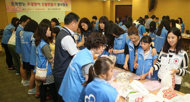 우리은행 임직원과 자녀가 12일 오전 서울 중구 우리은행 본사에서 열린 ‘축복받는 초경맞이 선물만들기 봉사활동’에서 대한적십자사 경기도지사 봉사자들과 함께 위생용품을 포장하고 있다. 이 행사는 취약계층 여성 청소년을 대상으로 위생용품 지원과 기초보건교육을 제공하기 위해 기획됐다. 연합뉴스