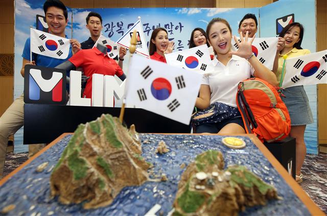 등산용품 업체 ‘엠리밋’ 모델들이 20일 오전 서울 세종문화회관 예인홀에서 태극기를 흔들며 광복 70주년 기념 독도 방문 행사를 알리고 있다. 엠리밋은 ‘엠포인트 카드’로 20만 원 이상 구매하는 고객을 대상으로 추첨을 통해 20명을 뽑아 동반 1인을 포함해 총 40명에게 독도 방문의 기회를 제공한다.  연합뉴스 