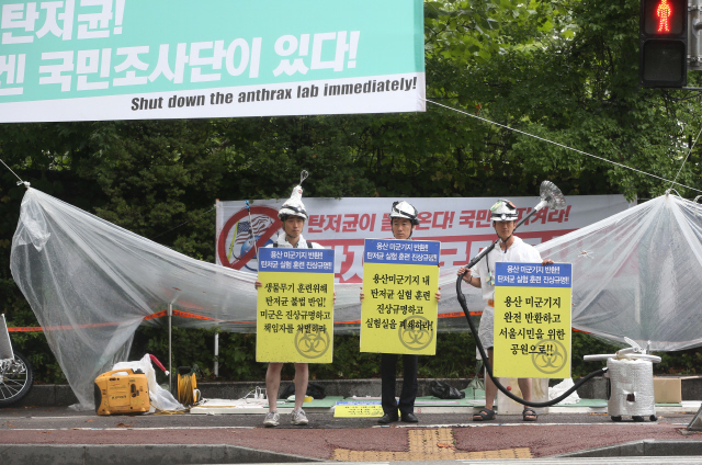 국방부가 탄저균 배달사고와 관련해 주한미군 오산기지 현장방문 등 신속한 조사로 사고의 진상을 규명할 것이라고 밝힌 24일 서울 용산구 미군기지 앞에서 민주민생평화통일주권연대 회원들이 ‘탄저균국민조사단’을 의미하는 복장을 하고 철저한 진상규명을 촉구하고 있다.  신소영 기자 viator@hani.co.kr