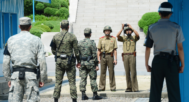 광복·분단 70돌의 해인 올해 7월27일 판문점 공동경비구역(JSA)에서 정전협정 62주년 기념식이 열린 뒤, 남과 북의 병사들이 군사분계선을 사이에 두고 서로 대치하고 있다. 한 북한군은 카메라를 들어 남쪽 기념식 참석자들의 동정을 촬영하고 있다.  판문점/사진공동취재단