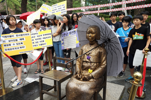 일본군 위안부 문제 해결을 위한 제1194차 정기 수요시위가 열린 2일 오후 서울 종로구 중학동 주한일본대사관 앞에서 갑자기 소나기가 내리자 한 학생이 가져다준 우산이 ‘소녀상’의 어깨 위에 놓여 있다.  이종근 기자 root2@hani.co.kr