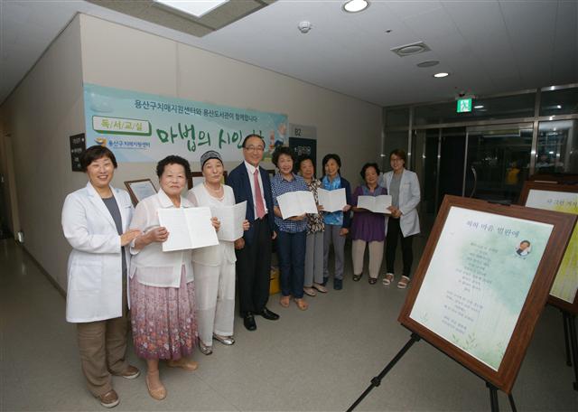 1. 지난 7월9일 서울 용산구 치매지원센터에서 열린 ‘마법의 시인’ 시화전에서 이말순(왼쪽 셋째)씨가 학생, 강사, 직원과 함께 기념사진을 찍었다. 용산구 제공, 원낙연 기자
