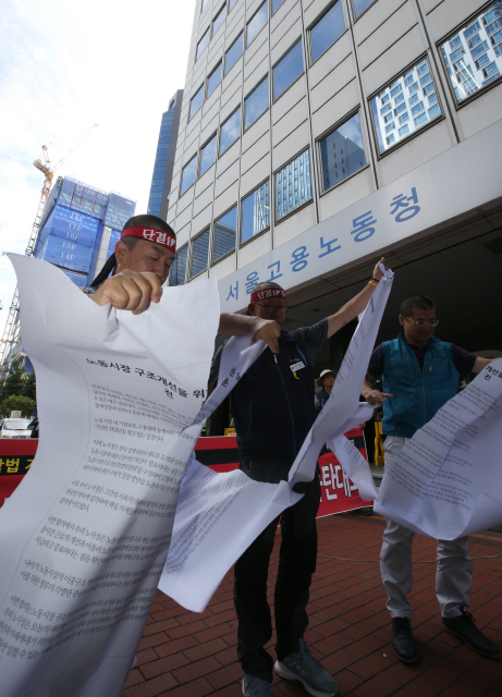 <b>찢겨지는 노사정 합의문</b> 16일 오후 서울 중구 장교동 서울고용노동청 앞에서 민주노총 산하 지부 조합원들이 노사정 합의를 “노동재앙을 불러올 최악의 합의”이자 ‘야합의 결과’라고 규탄하는 뜻으로 합의문 전문을 찢고 있다. 신소영 기자 viator@hani.co.kr