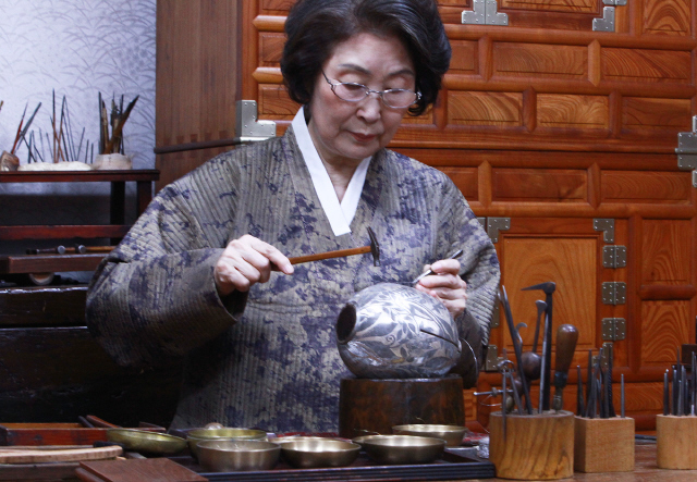 차가운 금속의 표면에 은실과 금실로 무늬를 입히면 따뜻한 인간의 정성이 견고하게 스며든다. 가장 세밀한 금속공예로 꼽히는 입사 기법은 현대 금속공예를 전공한 홍정실씨의 열정으로 맥이 끊겼다가 되살아났다. 홍 장인이 자신의 공방 길금공예연구소에서 작업을 하고 있다.