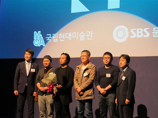 올해의 작가상 시상식장에 함께 선 후보작가들. 왼쪽에서 세번째 사람이 수상자 오인환 작가의 대역으로 나와 상 받는 연기를 펼친 배우다.  사진 국립현대미술관 제공