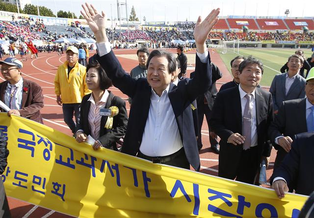 김무성 새누리당 대표가 25일 오전 서울 양천구 목동운동장에서 열린 제33회 대통령기 이북도민 체육대회에서 황해도중앙도민회가 만든 국정교과서 관련 펼침막을 배경으로 손을 들어 인사하고 있다.  연합뉴스