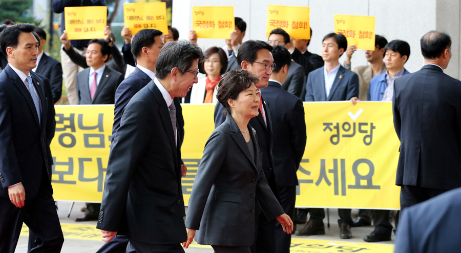 박근혜 대통령이 27일 오전 국회에서 시정연설을 하기위해 입장하고 있다. 그 뒤로 정의당 의원들이 국정화 반대 손팻말을 들고 시위를 하고 있다. 국회사진기자단