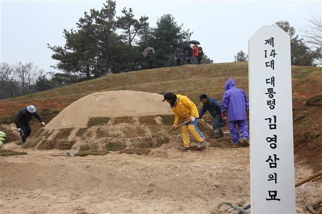 29일 오후 서울 동작구 국립서울현충원 장군 3묘역에 마련된 김영삼 전 대통령의 묘역에서 봉분 위에 잔디를 덮는 묘역 단장 작업이 진행되고 있다.   연합뉴스