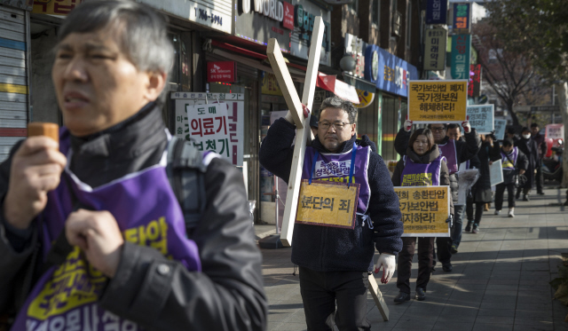 국가보안법이 제정된 지 67년째인 1일 오전 기독교평화행동목자단 회원들이 서울 종로구 한국기독교회관 앞에서 종각 쪽으로 십자가를 메고 행진하며 국가보안법 폐지 구호를 외치고 있다.  김성광 기자 flysg2@hani.co.kr