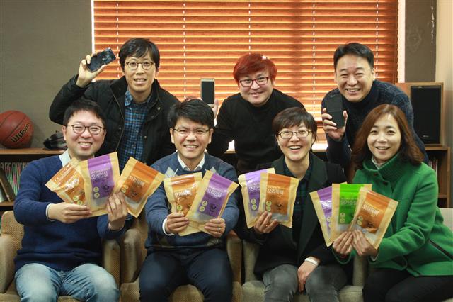 공동체이익회사 ‘굿바이’의 정경섭 대표이사(아래 맨 왼쪽) 등 구성원들이 자신들이 판매하는 휴대전화와 반려동물 간식을 손에 들고 포즈를 취하고 있다. 