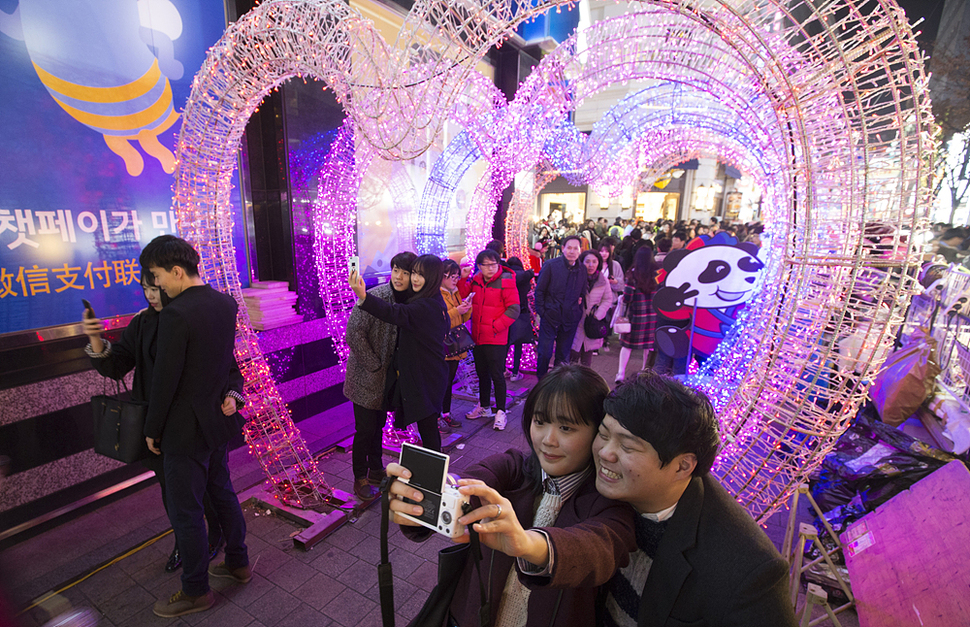 24일 저녁 서울 명동 거리로 나온 젊은이들이 하트 모양으로 꾸며진 조형물 아래서 기념사진을 찍고 있다. 김성광 기자 flysg2@hani.co.kr