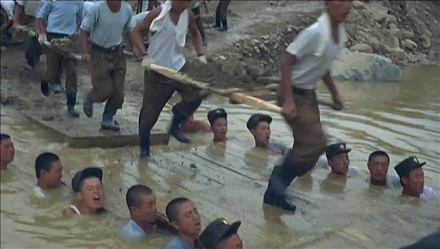 ‘인간 다리’ 만드는 북 병사들 북한 <조선중앙텔레비전>는 3일 ‘인민군대를 인민의 행복의 창조자로 이끌어 주시여’라는 제목의 새 기록영화를 방영했다. 1시간 분량의 영상에는 약 15명의 북한 병사들이 수심 1ｍ가 넘는 작은 개천에 들어가 ‘인간 다리’를 만드는 모습이 나온다.  조선중앙텔레비전 연합뉴스