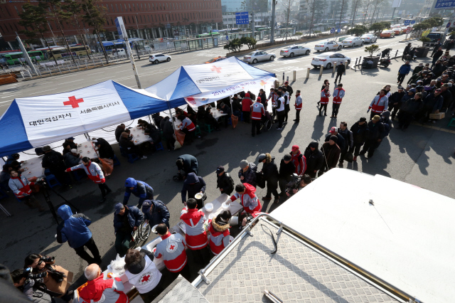  4일 오전 서울역광장에서 열린 대한적십자사 사랑의 떡국나눔 행사에서 봉사자들이 홀몸노인, 노숙인 등에게 떡국을 나눠주고 있다. 대한적십자사는 올해 시무식을 이날 떡국나눔 행사로 했다. 김태형 기자 xogud555@hani.co.kr