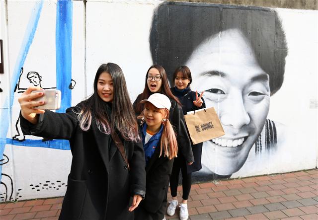 가수 김광석이 세상을 떠난 지 20년이 되는 6일 오후 대구 중구 대봉동 김광석길에서 시민들이 기념사진을 찍고 있다. 김광석의 출생지인 중구 대봉동 방천시장 주변은 음악 인생을 담은 문화공간으로 바뀌었다. 지난해 문화체육관광부의 한국 대표 관광지 100선에 선정된 이곳 ‘김광석 다시 그리기 길’에는 매주 7000여명의 관광객이 찾는다. 대구/연합뉴스
